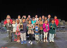  Group of children. Two children in front, one boy one girl from left to right are holding trophies